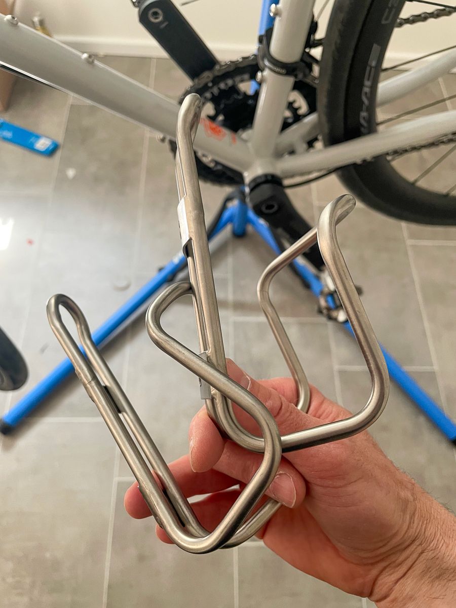 A hand holding two King Cage titanium bottle cages