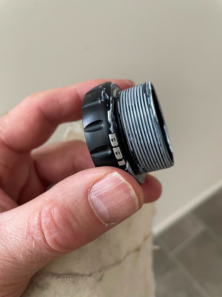 A hand holding the BB1 Bottom Bracket Cup. The cup is prepared with anti seize